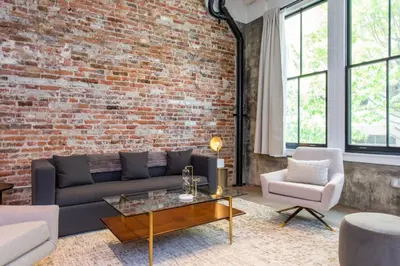 a living room with a couch and a brick wall at Inventors Loft Luxury Upscale Quiet Two Bedroom in Philadelphia