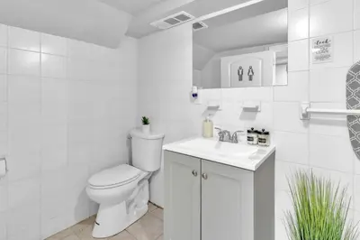 a white bathroom with a toilet and a sink at Cozy Private Apartment Near NYC Light Rail in Bayonne