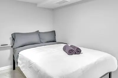 a white bed with two towels on top of it at Cozy Private Apartment Near NYC Light Rail in Bayonne
