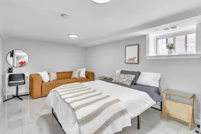a white bedroom with a bed and a couch at Cozy Private Apartment Near NYC Light Rail in Bayonne