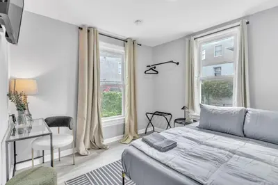 a bedroom with a bed and a desk and windows at Cozy Modern Apt Close to NYC NO STEPS or Stairs in South Hackensack