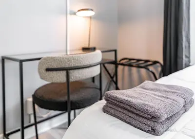 a chair sitting on a bed next to a table at Cozy Modern Apt Close to NYC NO STEPS or Stairs in South Hackensack