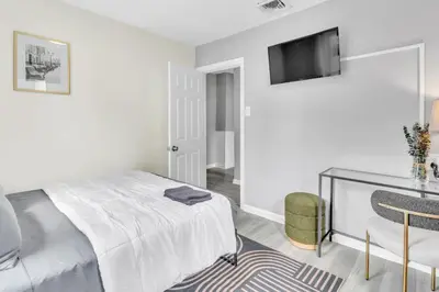 a white bedroom with a bed and a tv on the wall at Cozy Modern Apt Close to NYC NO STEPS or Stairs in South Hackensack