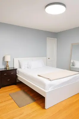 a white bedroom with a large bed and a lamp at Cozy Drexel Hill Retreat - Perfect for Families in Drexel Hill