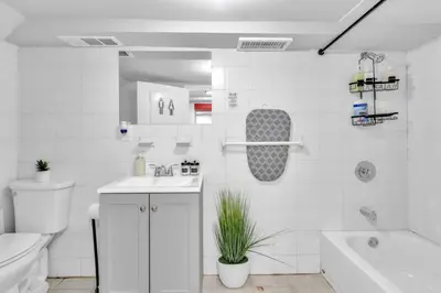 a white bathroom with a tub and a toilet and a sink at Cozy Private Room in Shared Space NYC Light Rail in Bayonne