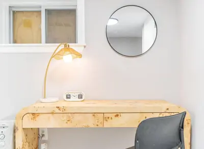 a wooden desk with a mirror and a lamp at Cozy Private Room in Shared Space NYC Light Rail in Bayonne