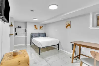 a bedroom with a bed and a table in a room at Cozy Private Room in Shared Space NYC Light Rail BSMT A in Bayonne