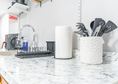a kitchen counter with two white vases filled with utensils at Cozy Private Room in Shared Space NYC Light Rail BSMT A in Bayonne