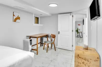 a bedroom with a bed and a table and a television at Cozy Private Room in Shared Space NYC Light Rail BSMT A in Bayonne