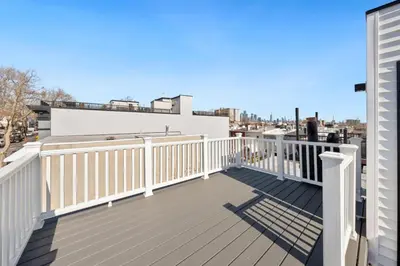 a balcony with white railings on a house at NYC Skyline Views • Near Times Sq • Rooftop Deck in Jersey City