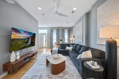 a living room with a blue couch and a tv at NYC Skyline Views • Near Times Sq • Rooftop Deck in Jersey City