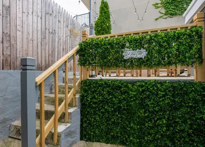 a fence covered in green ivy next to a staircase at Modern Condo with Private Porch, Mins to NYC in Jersey City