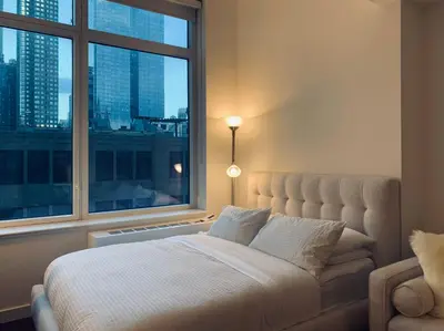 a bedroom with a bed and a large window at Entire luxury apt midtown with pool, gym, and sauna in New York
