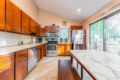 a kitchen with wooden cabinets and a large window at Switch to hosting Peaceful Lakefront Stay, HotTub, Fireplace, Kayaks in East Stroudsburg