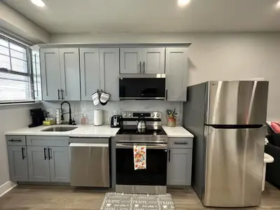 a kitchen with white cabinets and a stainless steel refrigerator at Chic New Apt in Heart of Philly in Philadelphia