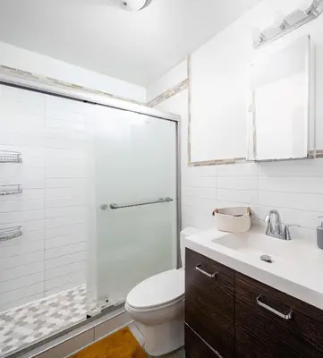 a bathroom with a toilet and a glass shower at Spacious 3BR Retreat Near Times Square in New York