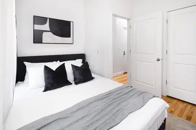 a white bedroom with a bed with black pillows at Spacious 3BR Retreat Near Times Square in New York