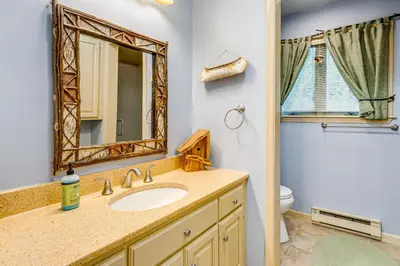 a bathroom with a sink and a mirror and a toilet at Beech Mt Lakefront Gem! Hot Tub, Kayaks, Billiards