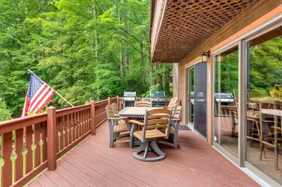 a deck with a table and chairs and an american flag at Beech Mt Lakefront Gem! Hot Tub, Kayaks, Billiards