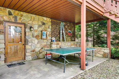 a ping pong table in front of a stone wall at Beech Mt Lakefront Gem! Hot Tub, Kayaks, Billiards