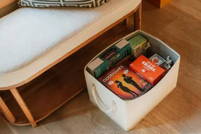 a white box under a bed with books at Tuthill Treehouse - Secluded Mountain Cabin with Roof Deck & Fire Pit in Pond Eddy
