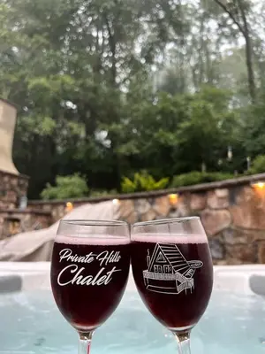 two wine glasses sitting on a table next to a pool at Fantastic A-Frame Cabin for a Couples' Getaway near Robesonia, Pennsylvania in Robesonia