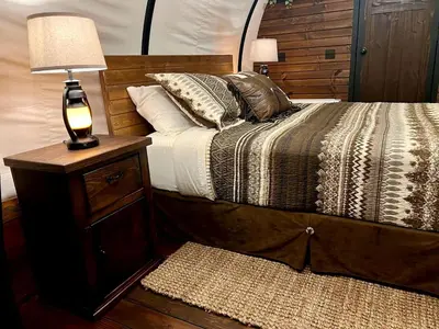 a bedroom with a bed and a lamp on a night stand at Elegant, Vintage Conestoga Covered Wagon Getaway in Denver, Pennsylvania in Denver