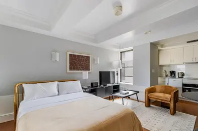 a bedroom with a bed and a chair and a kitchen at Blueground Upper West Side fitness nr Central Park NYC-1932 in New York