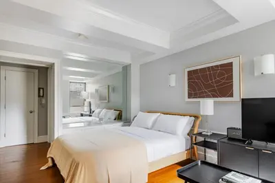 a white bedroom with a bed and a television at Blueground Upper West Side fitness nr Central Park NYC-1932 in New York