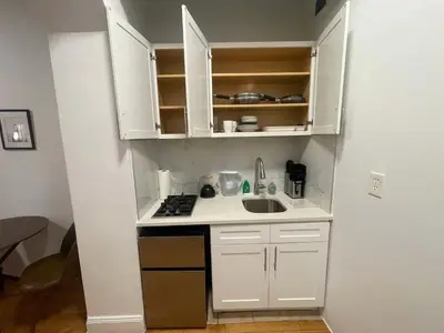 a small kitchen with white cabinets and a sink at Renovated Studio in Union Square in New York