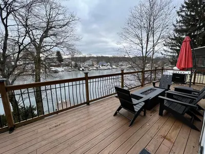 a deck with two chairs and a table and an umbrella at Cozy Cabin On the Lake with HotTub in Hopatcong