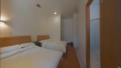two beds in a room with white sheets at U.S. Pacific Hotel in New York
