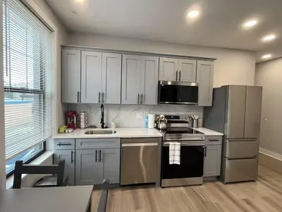 a kitchen with white cabinets and stainless steel appliances at New 1BR Walk to Pats & Genos in Philadelphia