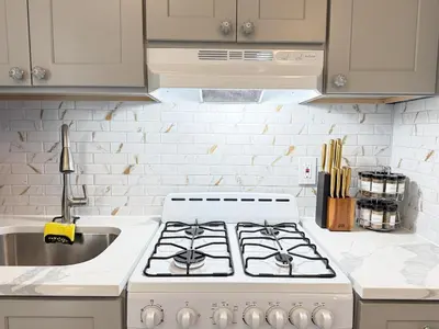 a white kitchen with a stove and a sink at New York City Dreams - 10 Mins in Union City