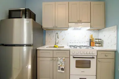 a kitchen with white cabinets and a stainless steel refrigerator at New York City Dreams - 10 Mins in Union City