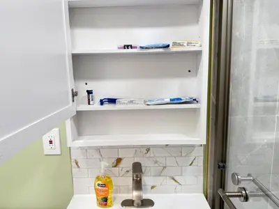 a bathroom with a sink and white shelves at New York City Dreams - 10 Mins in Union City