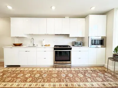 a white kitchen with white cabinets and appliances at The Executive - Center-City - 3BR-4Bath-Private-Garage in Philadelphia