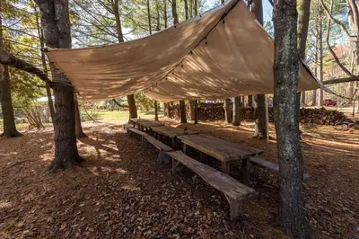 a blanket draped over a bench in a forest at Incredible Spacious Dome for A Group Glamping Experience Surrounded by Nature in Woodridge, New York in Woodridge