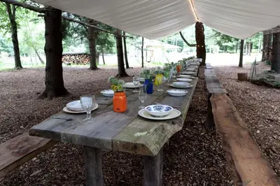 a long wooden table with plates and wine glasses on it at Cozy Unique Dome for a Romantic Glamping Getaway on a Private Farm in Woodridge, New York in Woodridge
