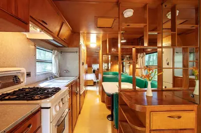 an rv kitchen with wooden cabinets and a stove at Gorgeous Fully Restored Caravan Nestled in the Trees Along Silver Lake for a Unique Vacation in Woodridge, New York in Woodridge