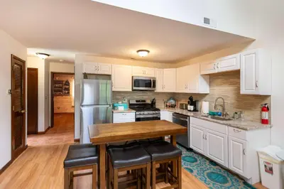 a kitchen with white cabinets and a wooden table at Cozy Loft Near Lake Trails and Mountain Views in Vernon Township