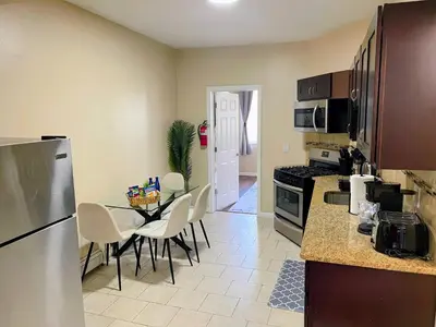 a kitchen with a table with chairs and a refrigerator at Cozy 2BR Brick Haven! Near light rail! 35m to NYC in Jersey City