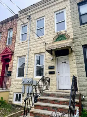 a stone house with a white door and stairs at Cozy 2BR Brick Haven! Near light rail! 35m to NYC in Jersey City