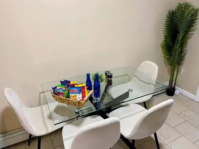 a glass table with white chairs and a basket of snacks at Cozy 2BR Brick Haven! Near light rail! 35m to NYC in Jersey City