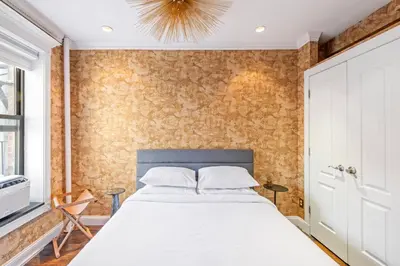 a bedroom with a large white bed with a brick wall at Studio Nolita in New York