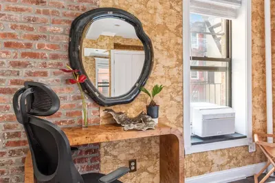 a mirror on a brick wall with a black chair at Studio Nolita in New York