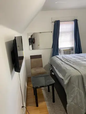 a bedroom with a bed and a chair and a television at Cjay home 3 in Jersey City