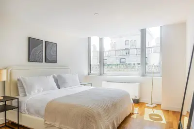 a white bedroom with a bed and two windows at Blueground Tribeca pool nr City Hall NYC-1930 in New York