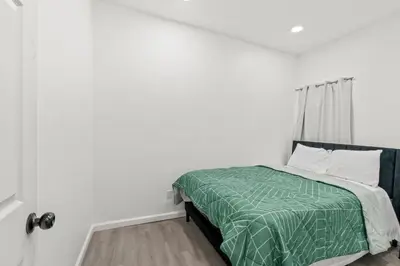 a white bedroom with a bed with a green comforter at The Soft Loft in Philadelphia