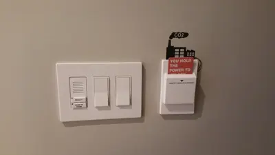 a white electrical outlet with a battery on a wall at NobleDEN Hotel in New York